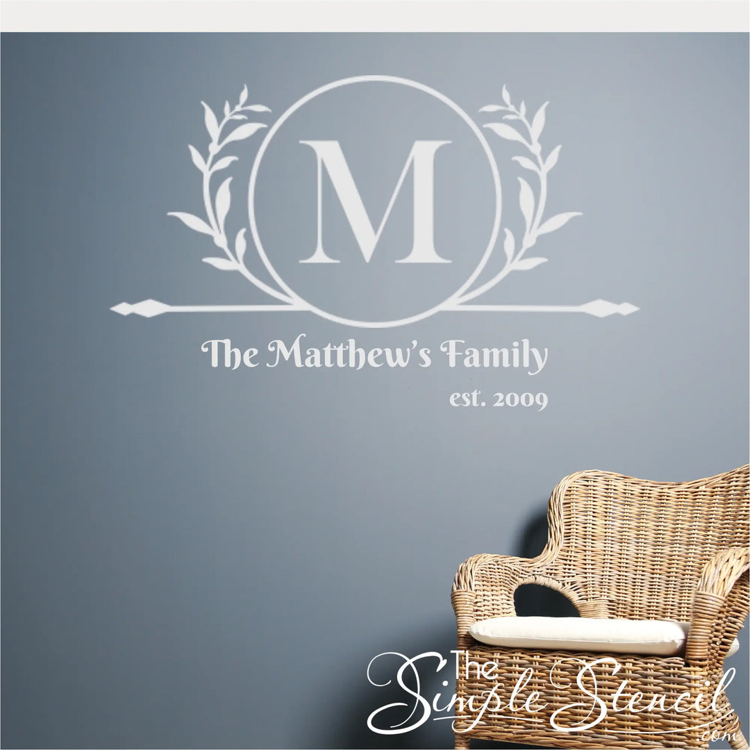 Wicker chair against a gray wall with decorative text and rotunda style monogram.