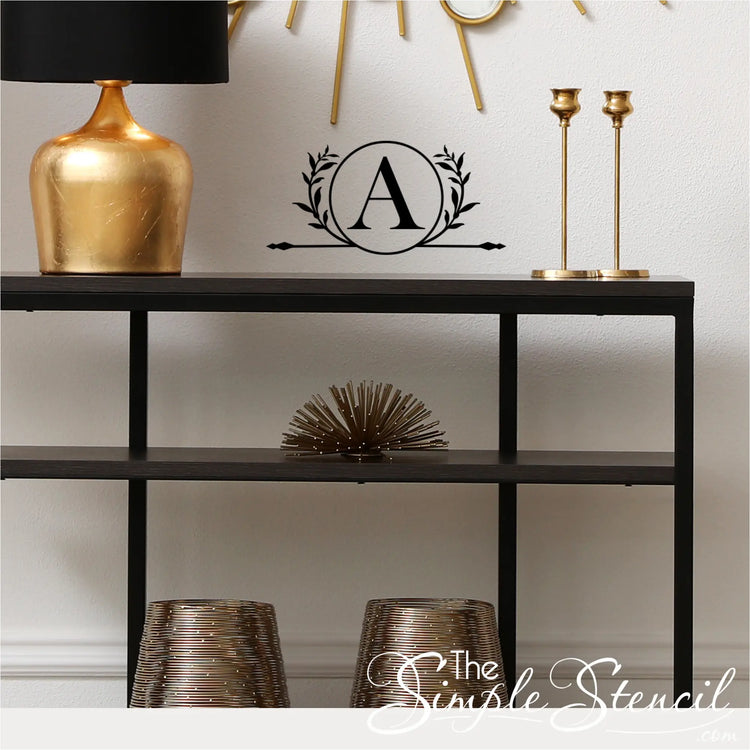 Decorative wall decal with a monogram letter 'A' above a shelf with decorative items.