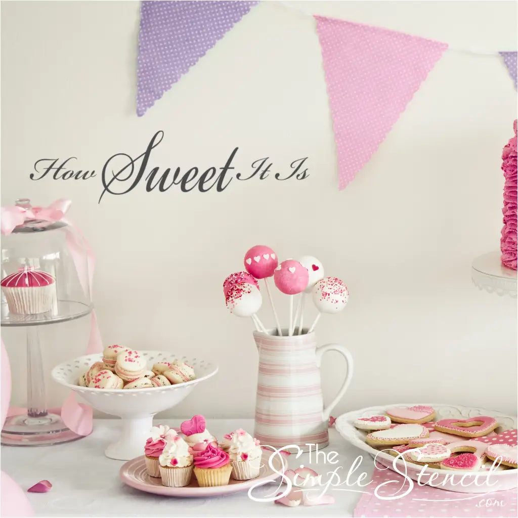 "How Sweet It Is" wall decal above a dessert table with cupcakes and cookies. By The Simple Stencil