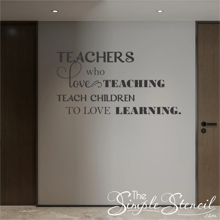 Large format school hallway wall decal 'Teachers who love teaching teach children who love learning' in dark grey vinyl on a neutral wall between classroom doors.