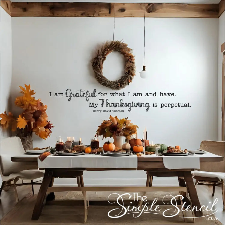 A beautifully set dining table decorated for Thanksgiving, with a black "I am grateful for what I am and have..." wall decal in elegant script above it. The scene features fall decor, including pumpkins and a rustic wreath, ideal for Thanksgiving decor and gratitude-themed wall art.