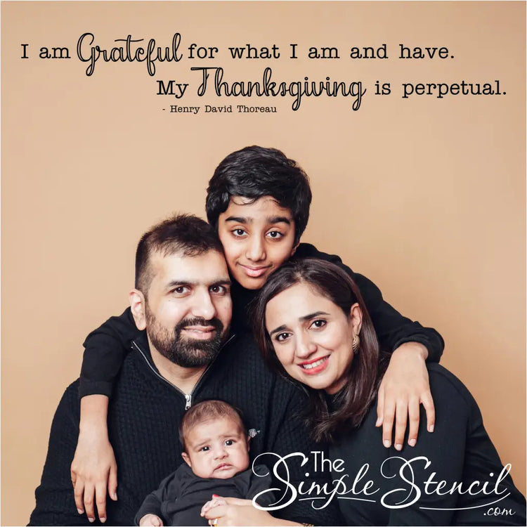 An inspirational wall decal with the Thoreau quote, "My thanksgiving is perpetual," placed above a family portrait, creating a heartwarming and meaningful focal point. This image is perfect for marketing the decal as decor for a family photo wall and as a unique family gift.