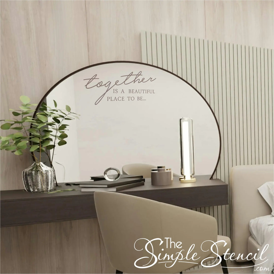 Elegant taupe script wall decal reading "Together is a beautiful place to be" applied to a large round vanity mirror in a modern, neutral-toned master bedroom.
