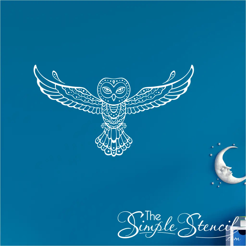 A white tribal owl vinyl decal on a vibrant blue wall above a modern white and blue storage cabinet.