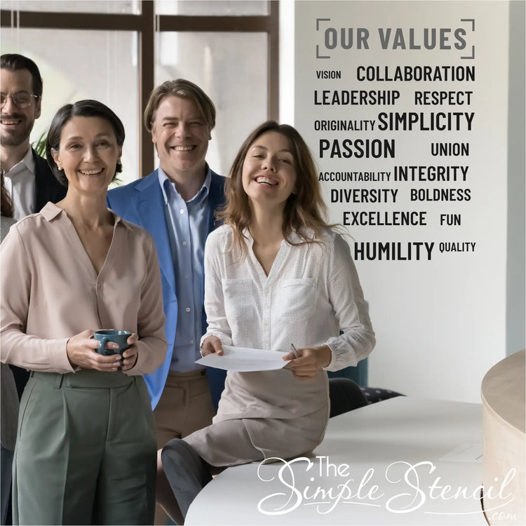 Employees collaborating in a meeting room with the "Our Values" wall decal set in the background.
