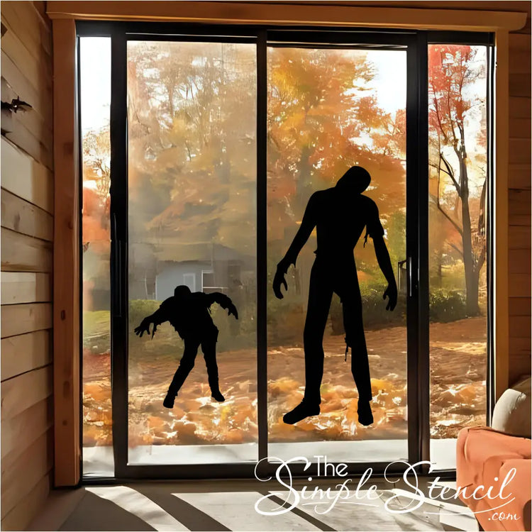 A black walking zombie silhouette vinyl decal on a sliding glass door, with an autumn forest in the background.
