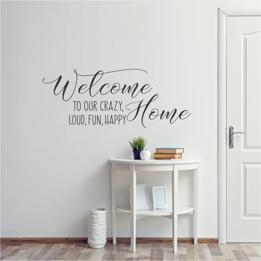 A beautiful foyer entryway with a stylish wall decal that welcomes you home and reads: Welcome to our crazy, loud, fun, happy home! By The Simple Stencil