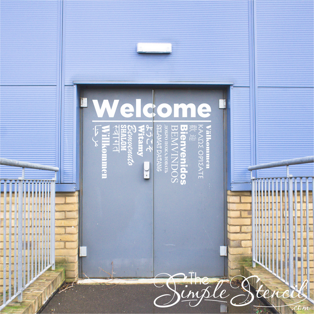 Large Welcome in 15 languages decals installed on two entry doors leading to a gym at a school that frequently hosts foreign students. 