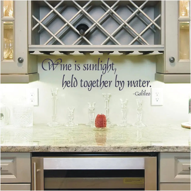 Wall quote decal by Galileo to decorate a wine cellar or near a wine rack. Reads: Wine is sunlight held together by water.