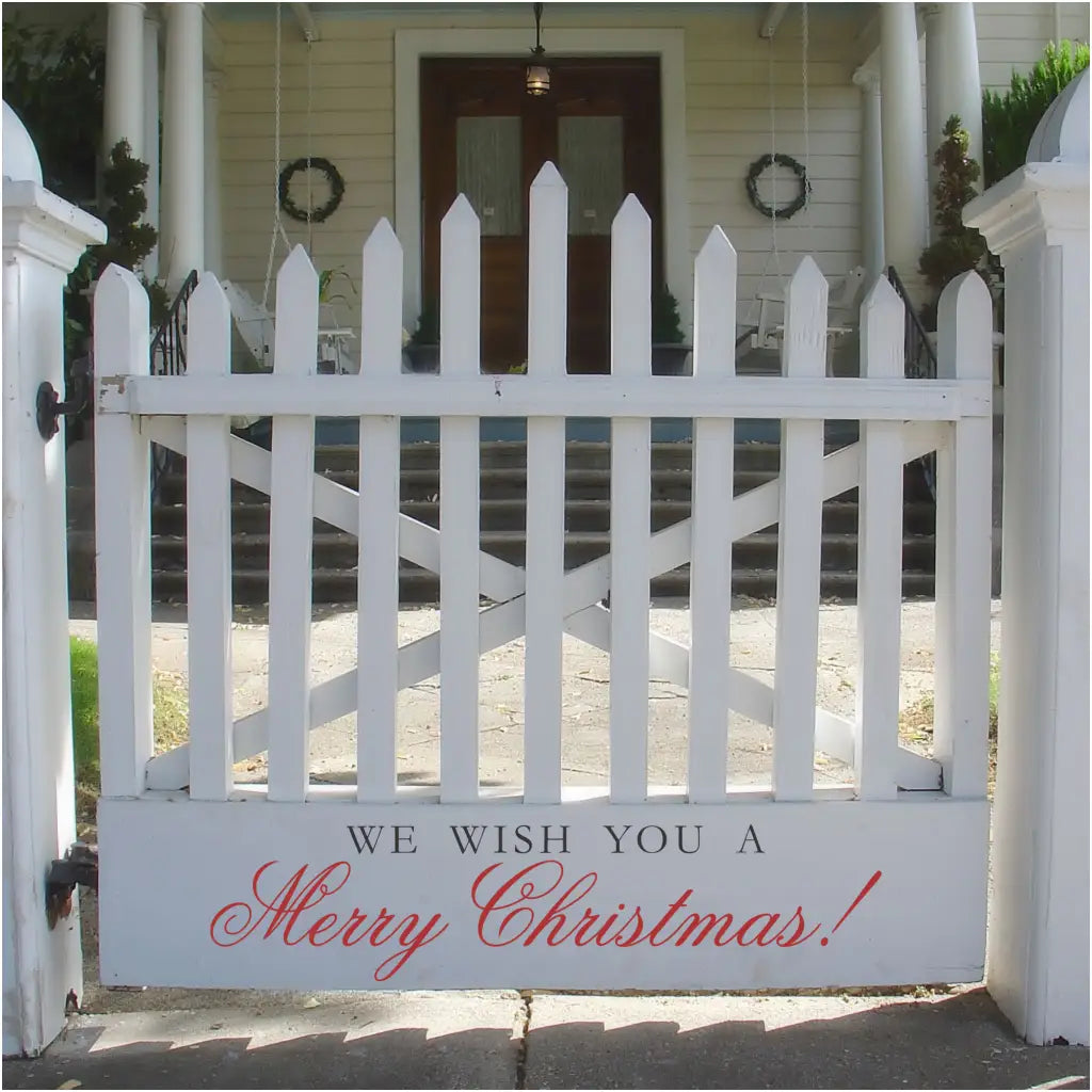 we wish you a merry christmas vinyl decal installed on an entryway gate to a home offering a festive message to the neighbors as they pass by during the holidays. Available in many sizes and colors from The Simple Stencil
